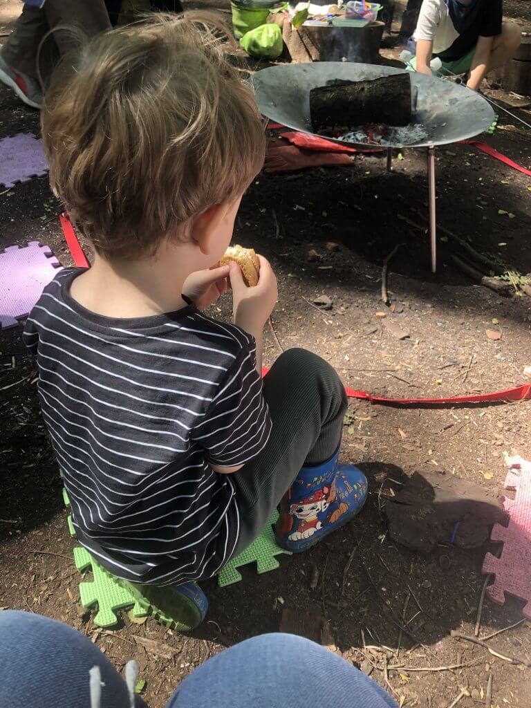 Boy by firepit eating marshmallow.